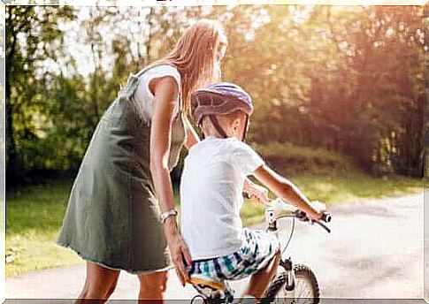 mother helping boy ride a bike