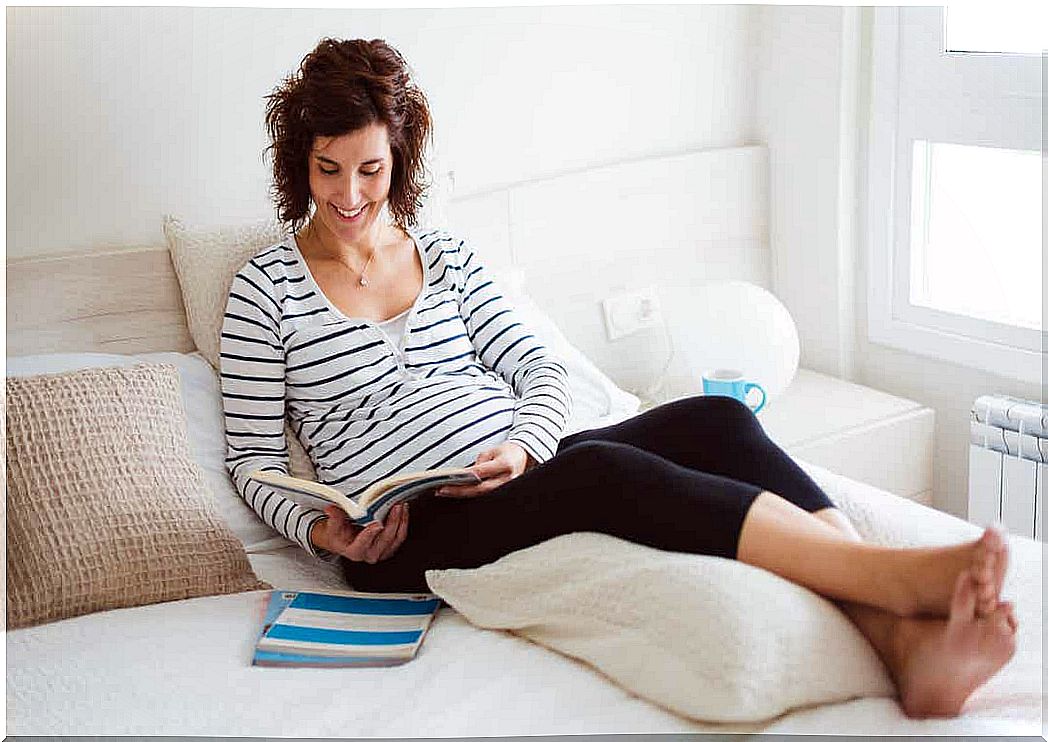 A pregnant woman sitting in bed reading a book of names