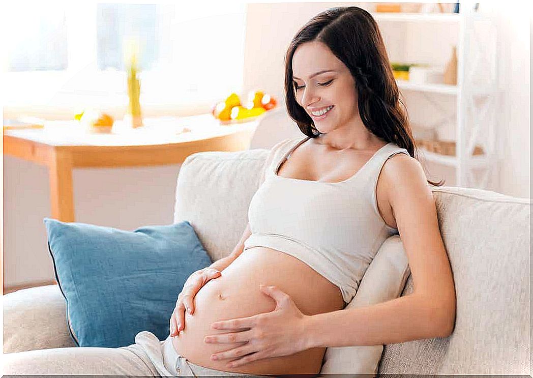 A pregnant woman with her hands on her bare stomach