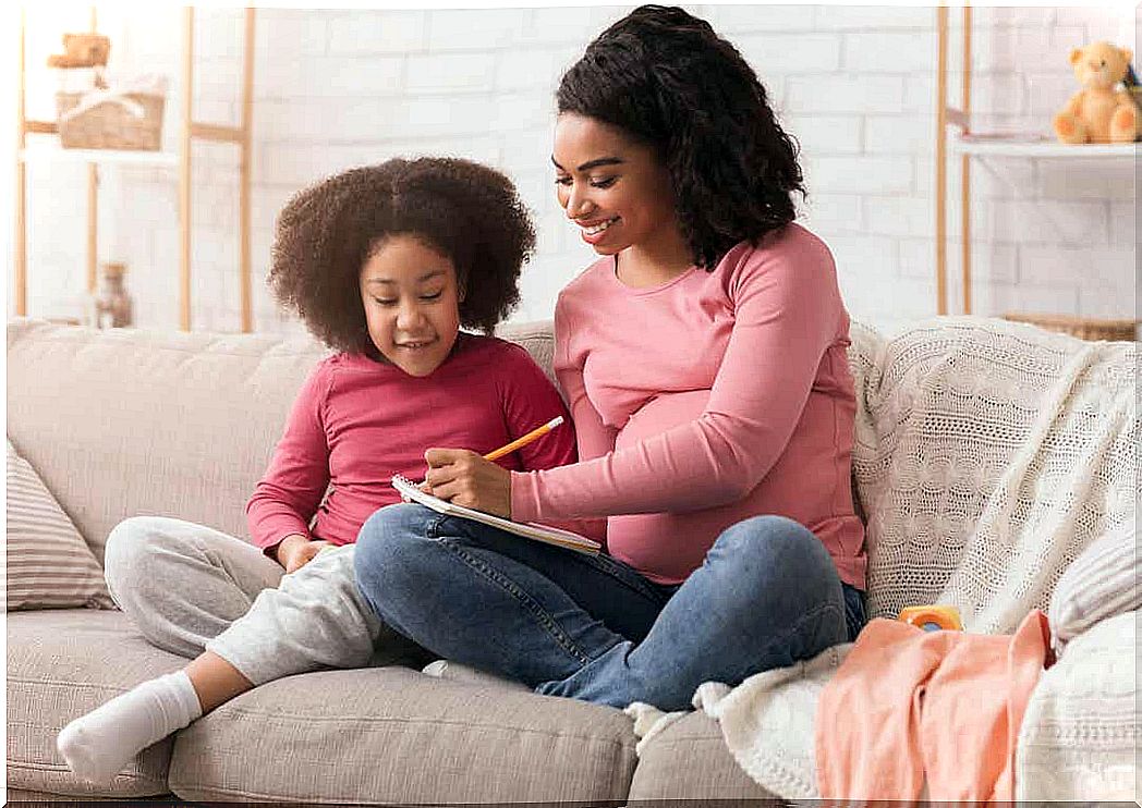 A pregnant woman sits with her young daughter and chooses names