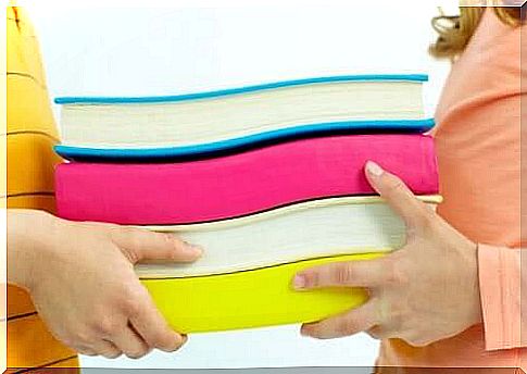 boy and girl holding a pile of books