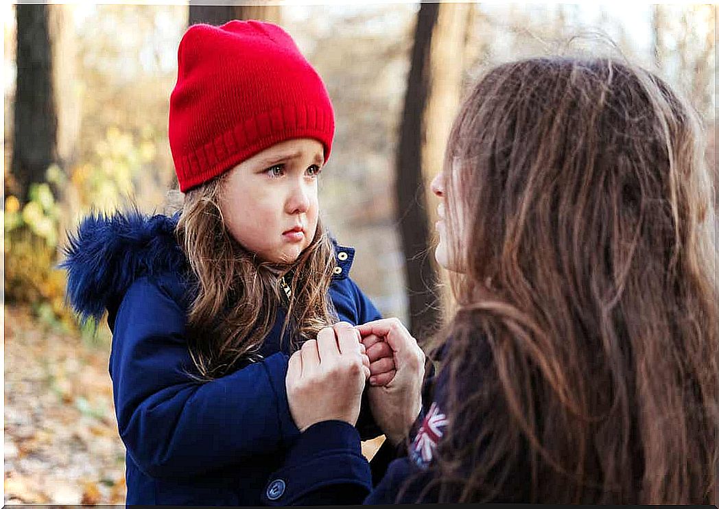 A mother who crouches down to talk to her little daughter who looks sad