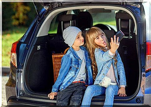 small children taking selfie in trunk of car