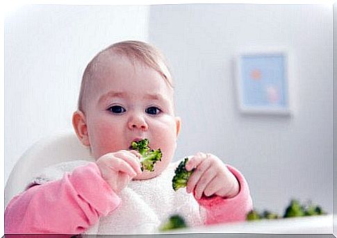 baby eating broccoli with his fingers