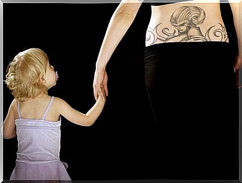 mother with lumbar tattoo holding daughter in hand