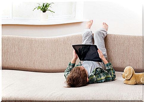 child lying on sofa with a tablet