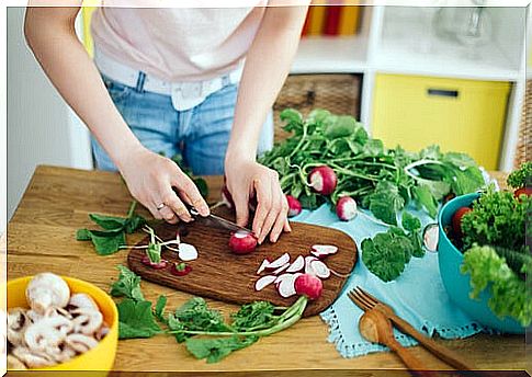 woman cutting radishes out on cutting board