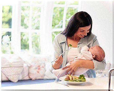 mother eating while holding her baby on her arm