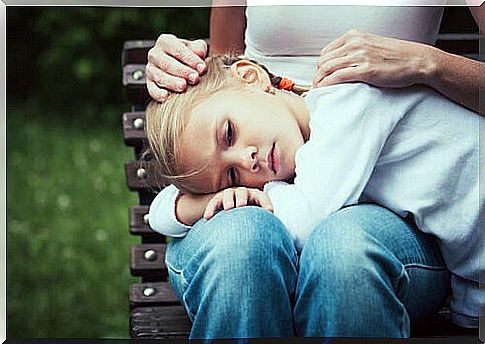 girl with her head in mother's lap on a bench outside