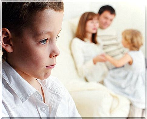 thoughtful little boy with his family in the background