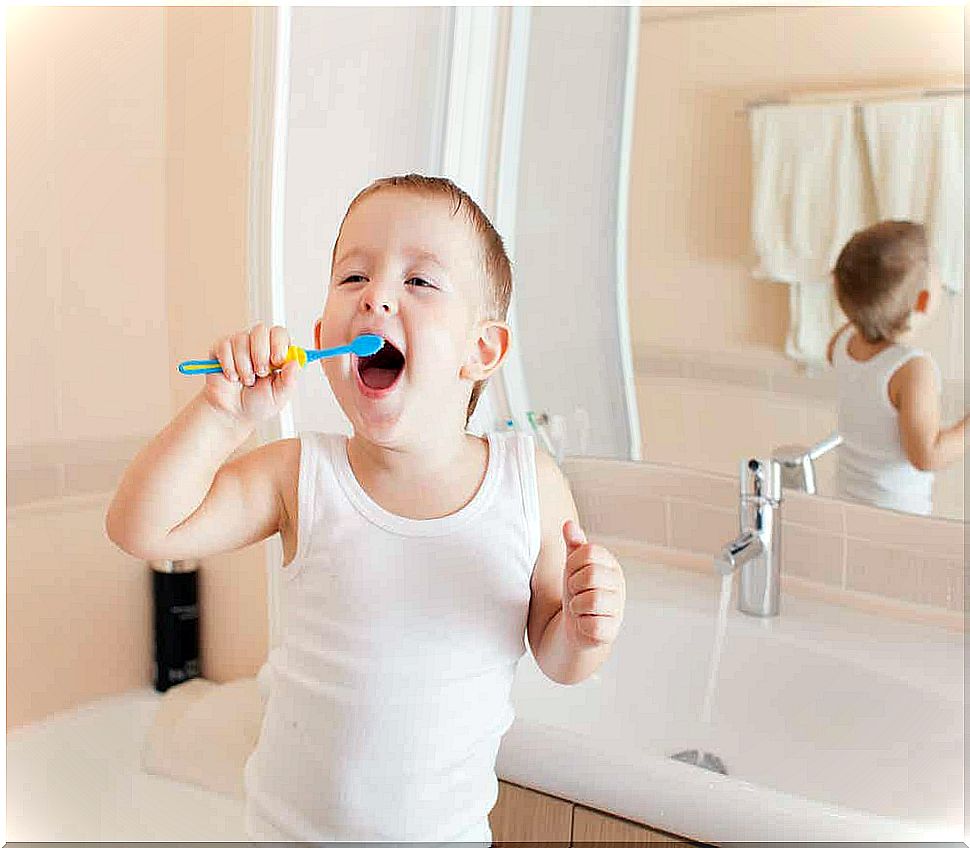 A little boy brushing his teeth and smiling