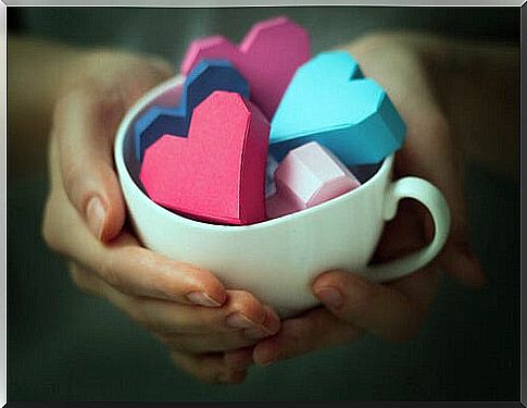 hands holding a coffee cup with hearts