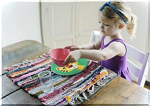 girl sitting at the table with bowl, plate and glass