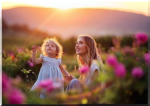 mother and daughter on a flower meadow at sunset