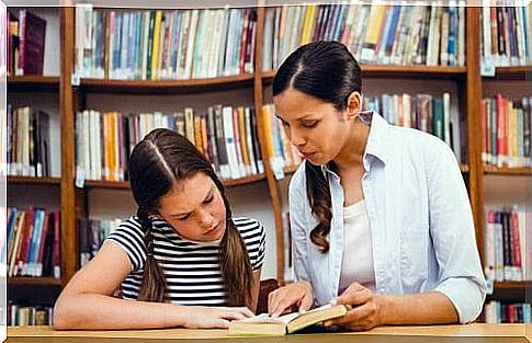 mother helping daughter with reading at library