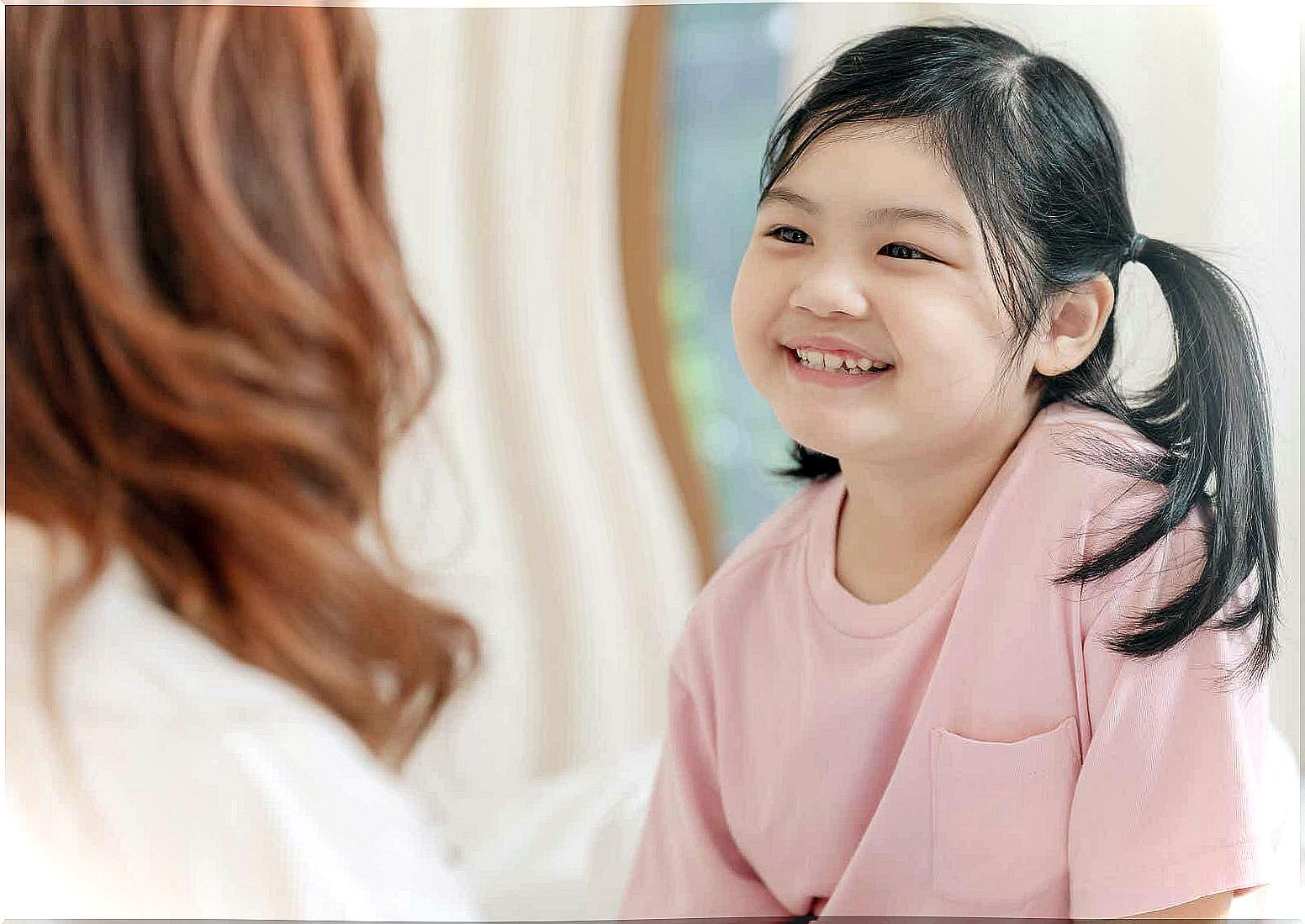 A young girl happily receives praise from her mother