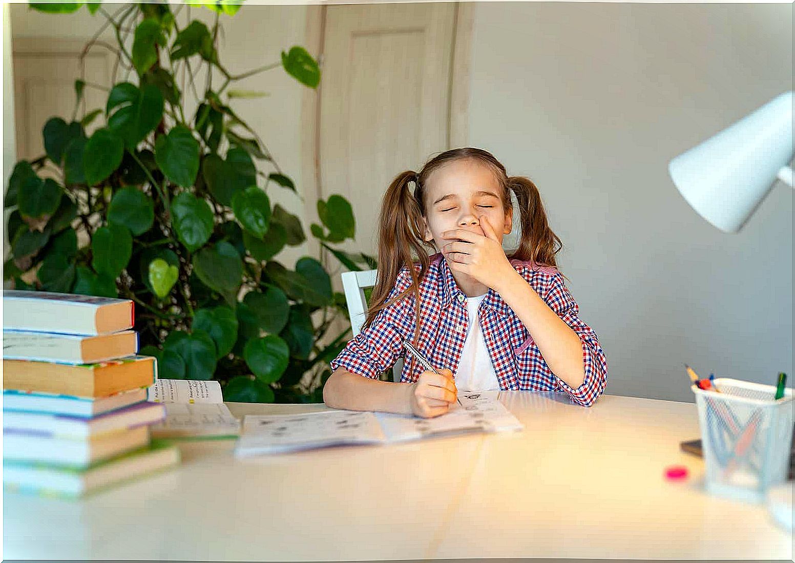 A teenage girl yawns while doing homework